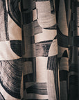 Black and tan abstract jacquard fabric hung as floor-length curtains falling in soft folds
