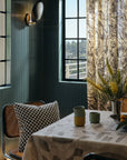 Black and cream checkerboard throw pillow styled as a throw pillow in a green panelled dining room