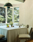 Brown striped linen wallpaper hung on the wall in a sunlit breakfast nook with checkerboard chairs