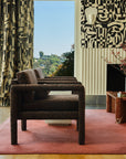 Black and tan abstract jacquard fabric hung as floor-length curtains in a living room with patterned walls and curtains