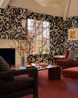 Black and cream checkerboard jacquard fabric made up as a throw pillow across a living room with a velvet sofa