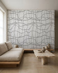 Black hand-drawn grid on white wallpaper installed in a minimalist living room