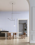 Modern dining room with white and blue grid-patterned wallpaper, a minimalist pendant light, sculptural wooden furniture, and a black sideboard, creating a contemporary and stylish aesthetic.