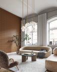 Modern living room featuring a warm brown grid-patterned wallpaper, plush cream-colored seating, a shaggy white rug, and a sculptural glass pendant light, creating a cozy yet sophisticated ambiance.