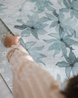 light blue floral pattern wallpaper with hand holding the edge of the paper