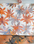 Hand holding two orange floral wallpaper pattern panels