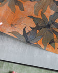 Close up of female hand holding orange floral wallpaper panel