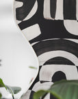 Down the Rabbit Hole Wallpaper Design Installed on Wall with Organic Shaped Mirror and Green Leaves in Foreground