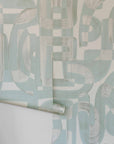 Green and tan colored Down the Rabbit Hole Wallpaper Rolls shown on an interior wall