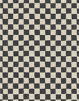 Close-up of black and white checkered grasscloth wallpaper with a woven texture, featuring subtle irregularities in the pattern for a handcrafted look.