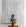 Modern interior with a large hanging panel of gray-toned abstract wallpaper featuring vertical brushstroke stripes, complemented by a potted fiddle-leaf fig on a woven table.