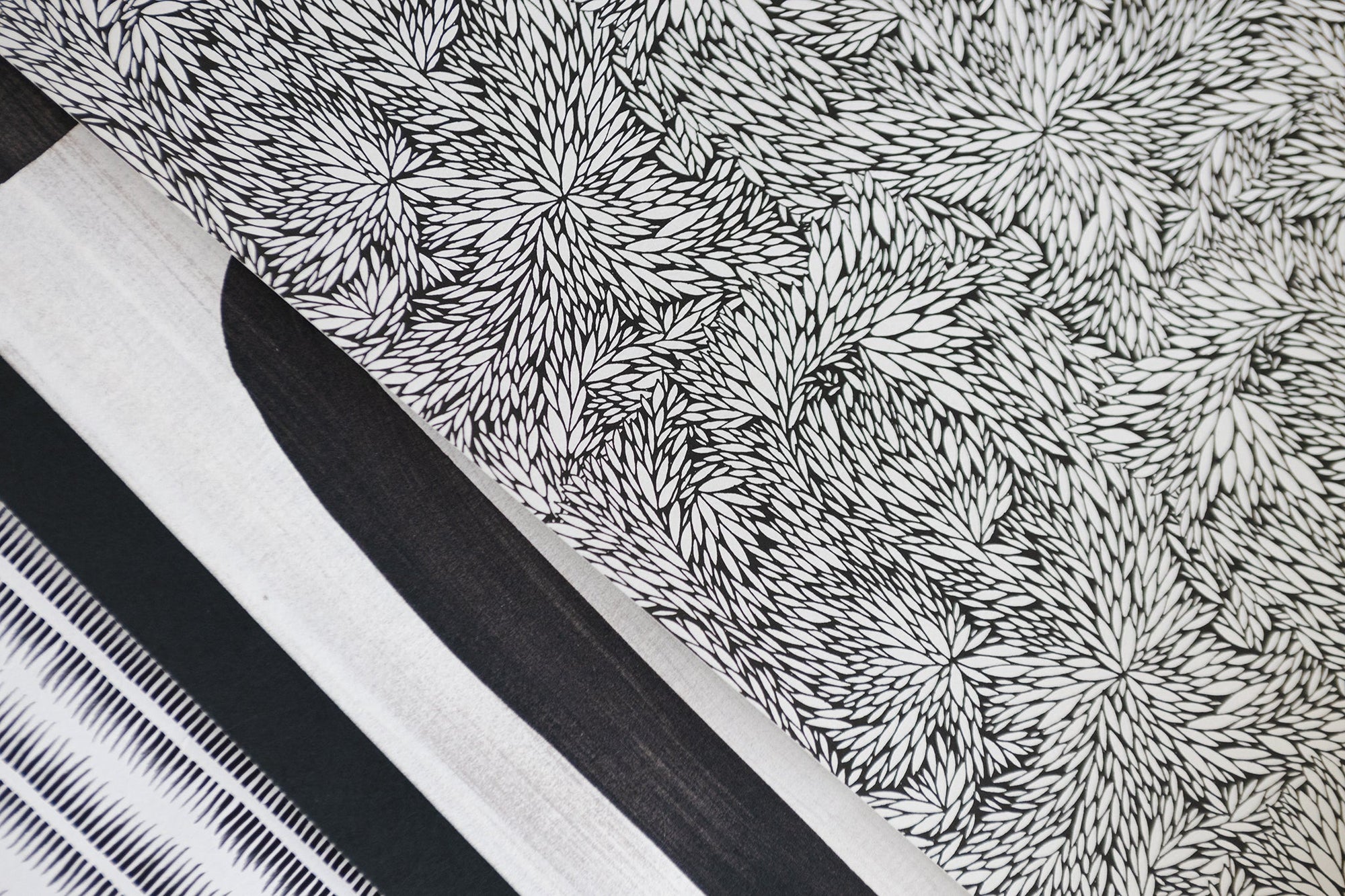 A selection of patterned wallpaper panels, featuring a black-and-white botanical print with a dense, abstract leaf design among other monochrome prints.
