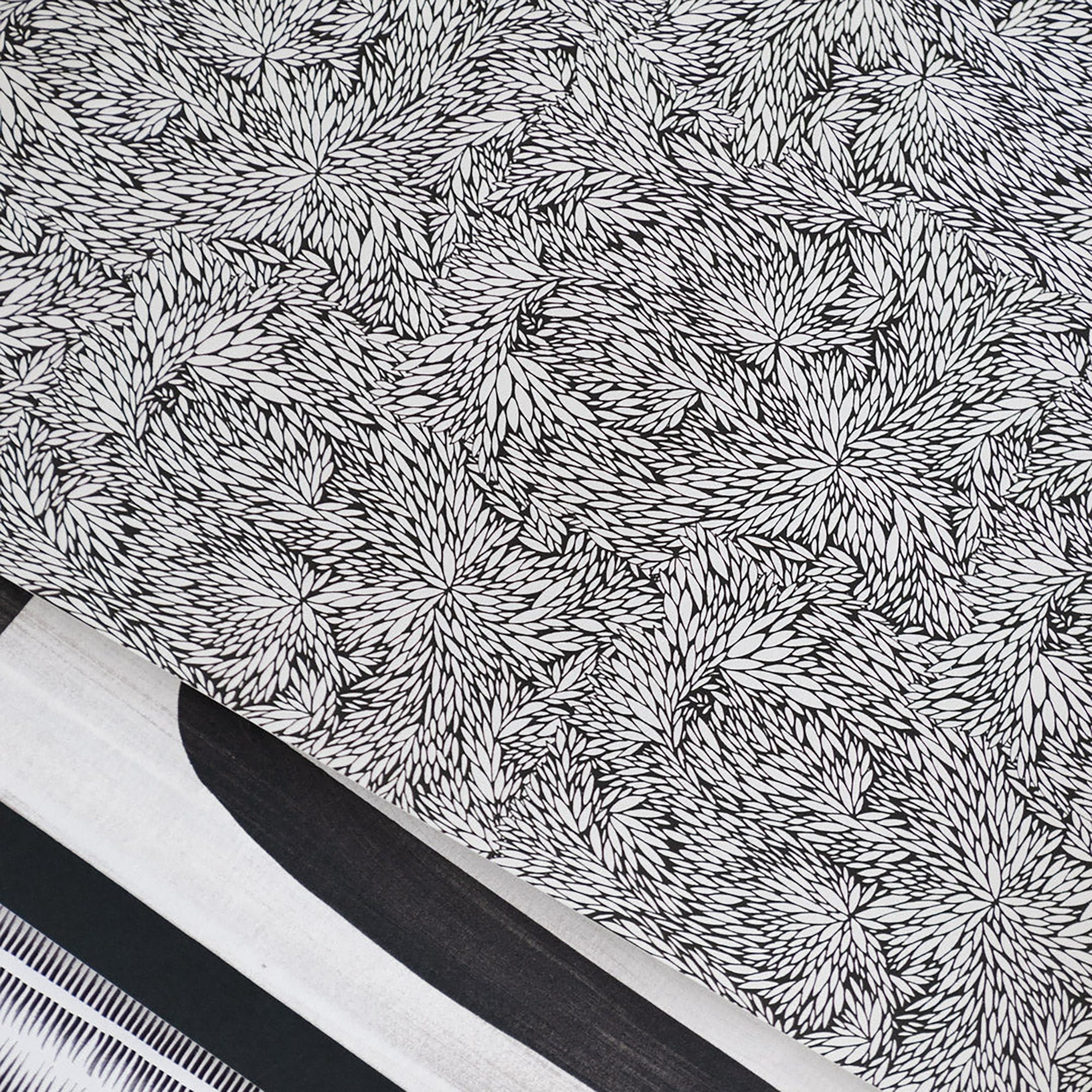 Close up of black and white botanical wallpaper with an intricate, abstract leaf pattern, layered among wallpaper prints