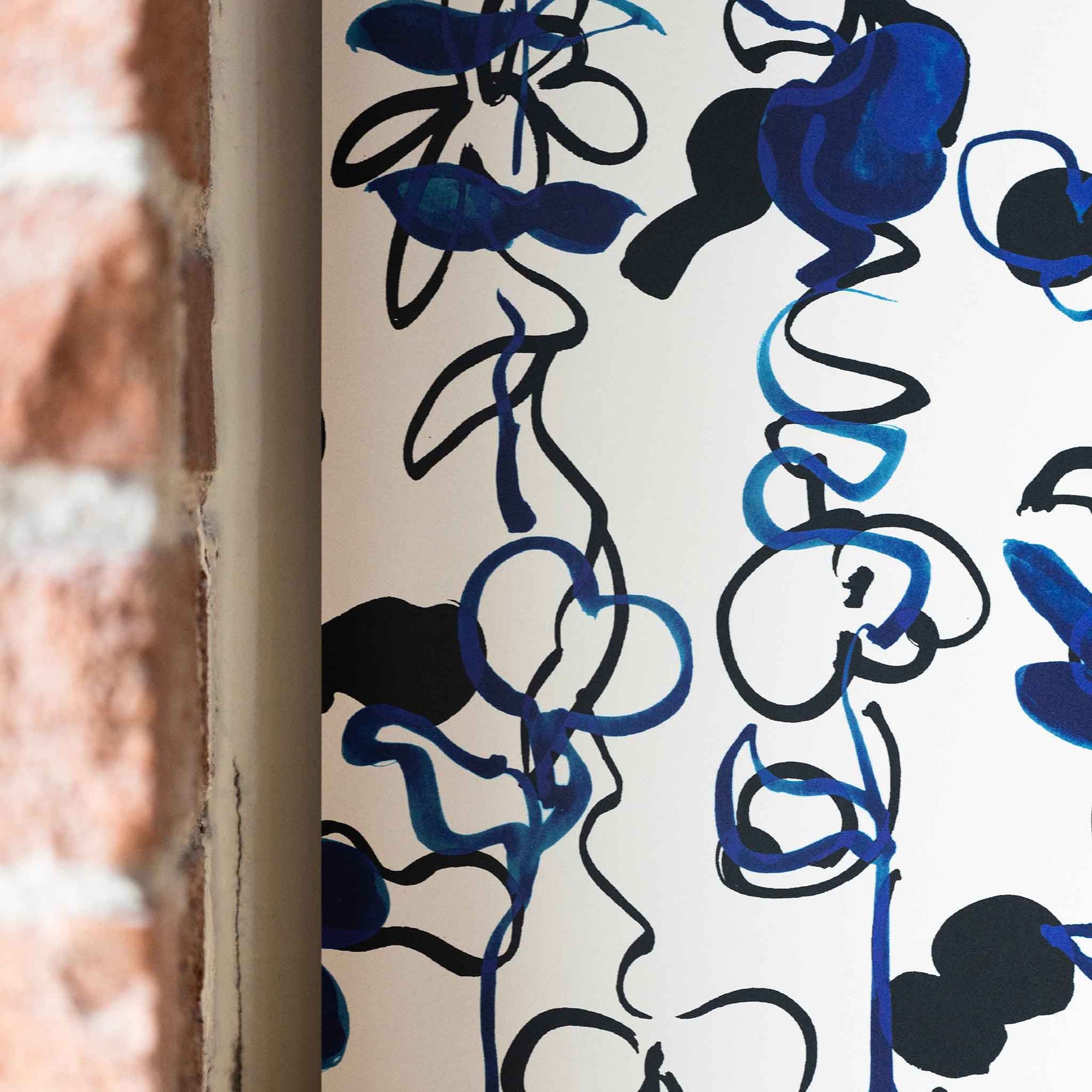 Close up Abstract floral wallpaper with hand-drawn botanical elements in deep blue and black tones on a white background, creating a dynamic and artistic design with brick wall in foreground