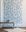 Charming wallpaper with hand-drawn blue bows on a pale blue background, styled with a modern metallic coffee table and a plush white rug.