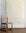 Cheerful wallpaper with hand-drawn yellow bows on a white background, styled with a natural wood chair and rustic wood flooring.