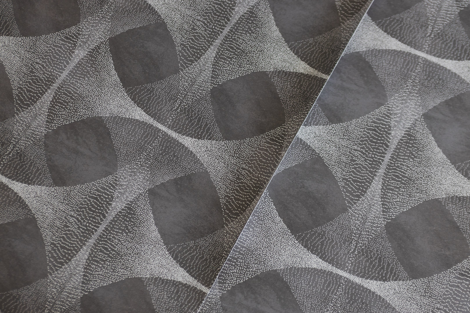 Modern dark grey wallpaper with an abstract geometric pattern of interconnected curved shapes, highlighted by delicate white dotted detailing, creating a dynamic, textured effect.