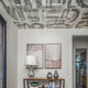 Modern entryway featuring an abstract brushstroke Down the Rabbit Hole wallpaper applied to the ceiling, with a neutral-toned console table, decorative vases, and framed artwork on the wall.
