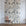 Grasscloth wallpaper of a large floral printed on grasscloth, staged on a white brick wall with a wooden chair