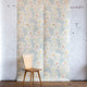 Floral grasscloth wallpaper with a wooden chair and lamp against a white brick wall.