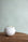 Soft light blue textured wallpaper with a woven finish, styled with a wooden side table and a single white ceramic vase.