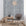 Bohemian-style living room with a deep gray textured wallpaper featuring vertical brushstroke stripes, styled with woven baskets, vases, and a rattan chair.