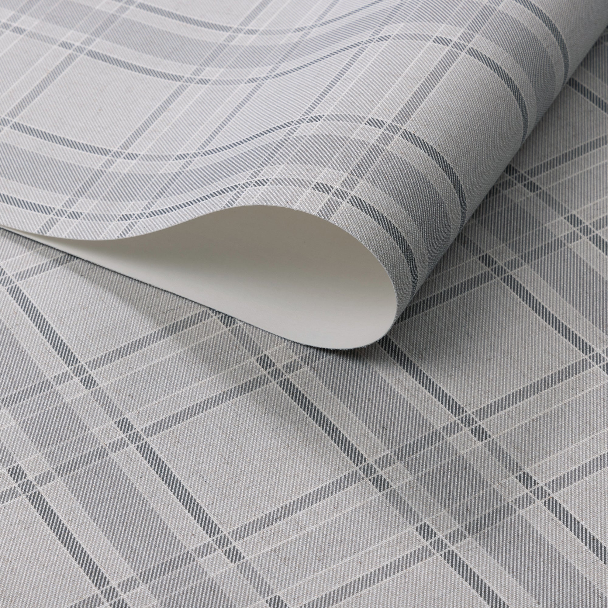 Light grey wallpaper with a classic plaid pattern in soft charcoal and white tones, shown in a rolled detail to highlight texture and print.