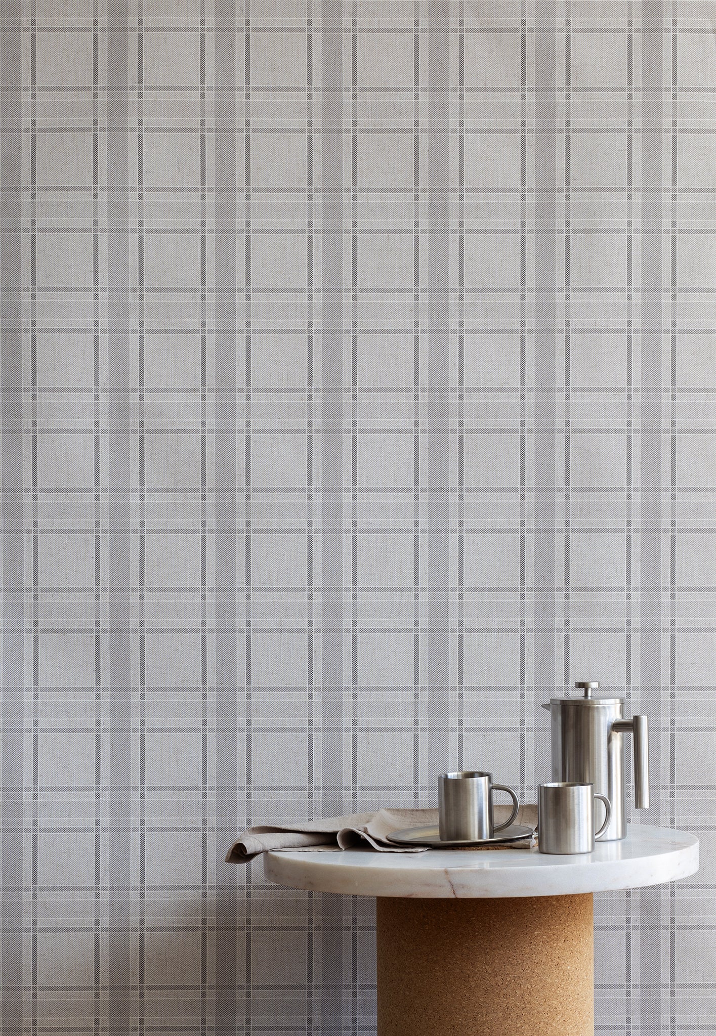 Modern kitchen scene with a minimalist round table and stainless steel accessories set against a light grey plaid wallpaper backdrop.