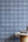 Styled kitchen setting with a marble and cork table against a blue plaid wallpaper, creating a cozy yet modern atmosphere
