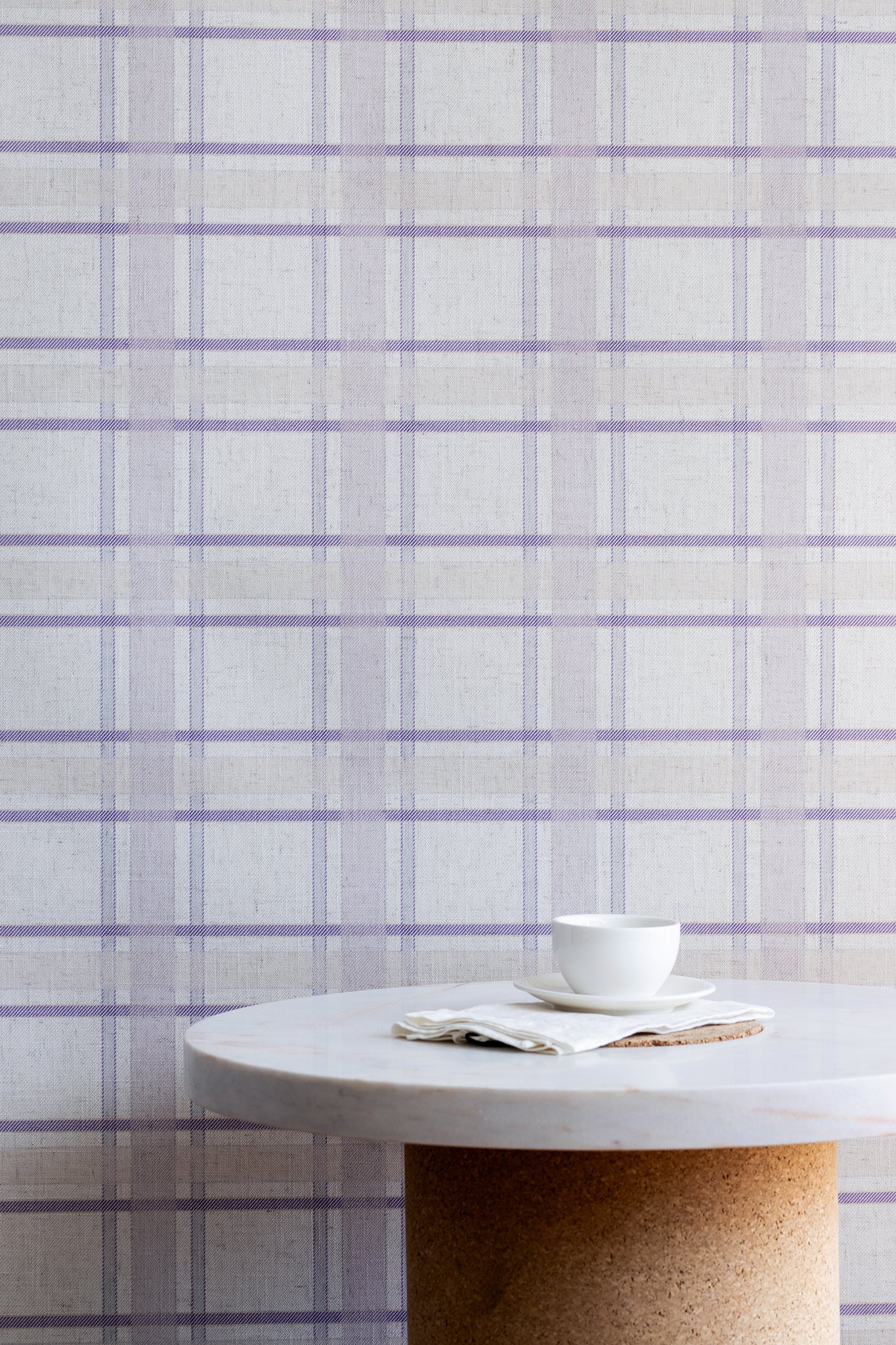 Minimalist kitchen scene with a marble and cork table set against a lavender plaid linen wallpaper, creating a gentle and calming interior look.