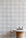 Serene interior scene with a marble and cork table set in front of a pastel plaid wallpaper, creating a light and airy atmosphere.