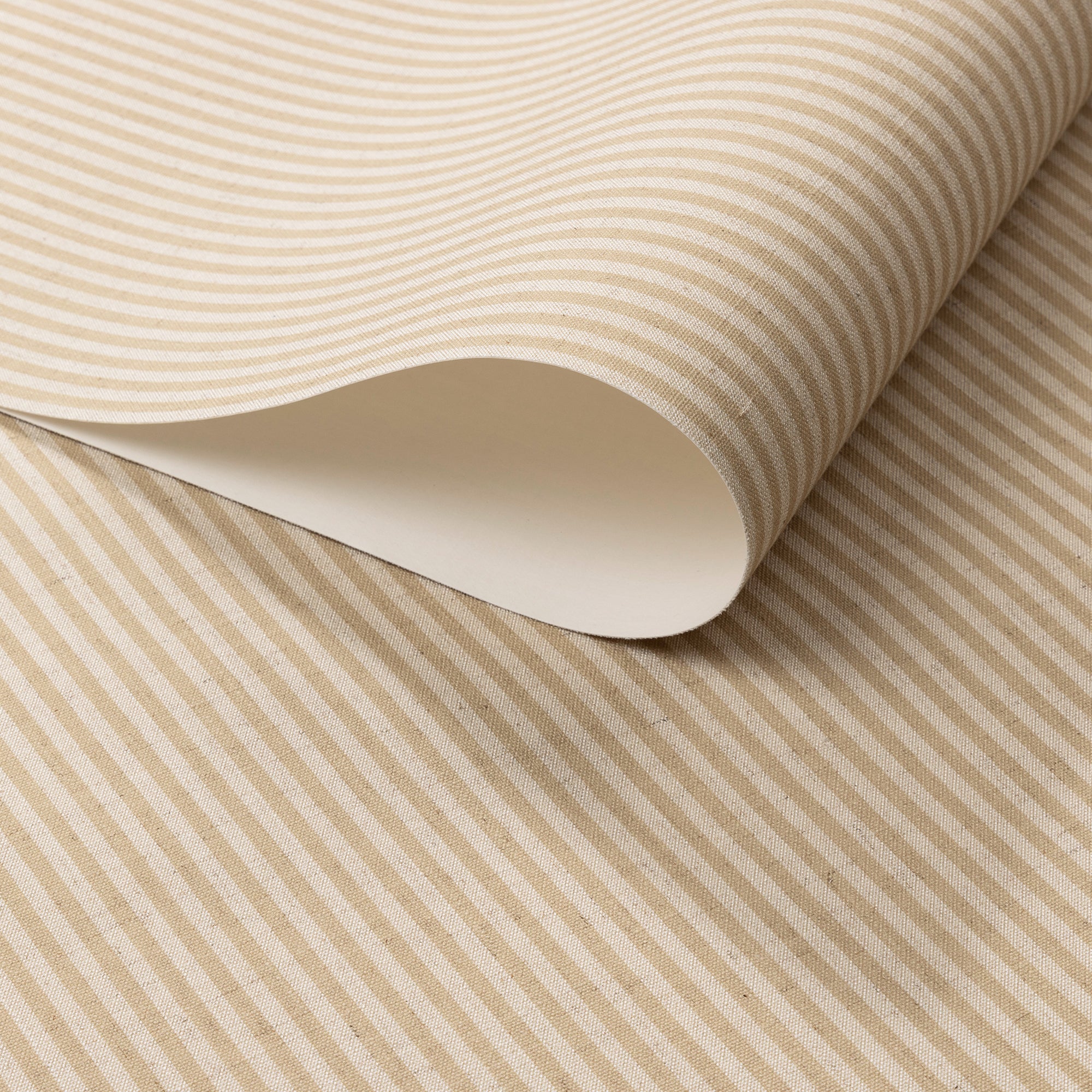 Close-up of real linen wallpaper roll with warm tan and cream vertical stripes.