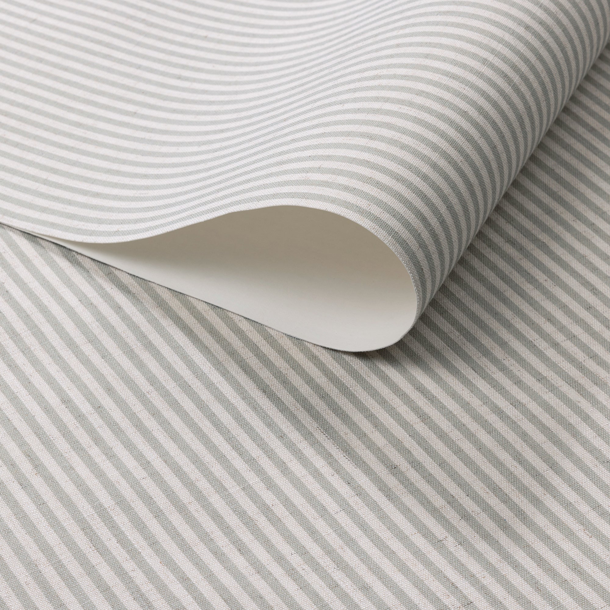 Close-up of wallpaper roll featuring narrow sage green and cream stripes on a natural linen.