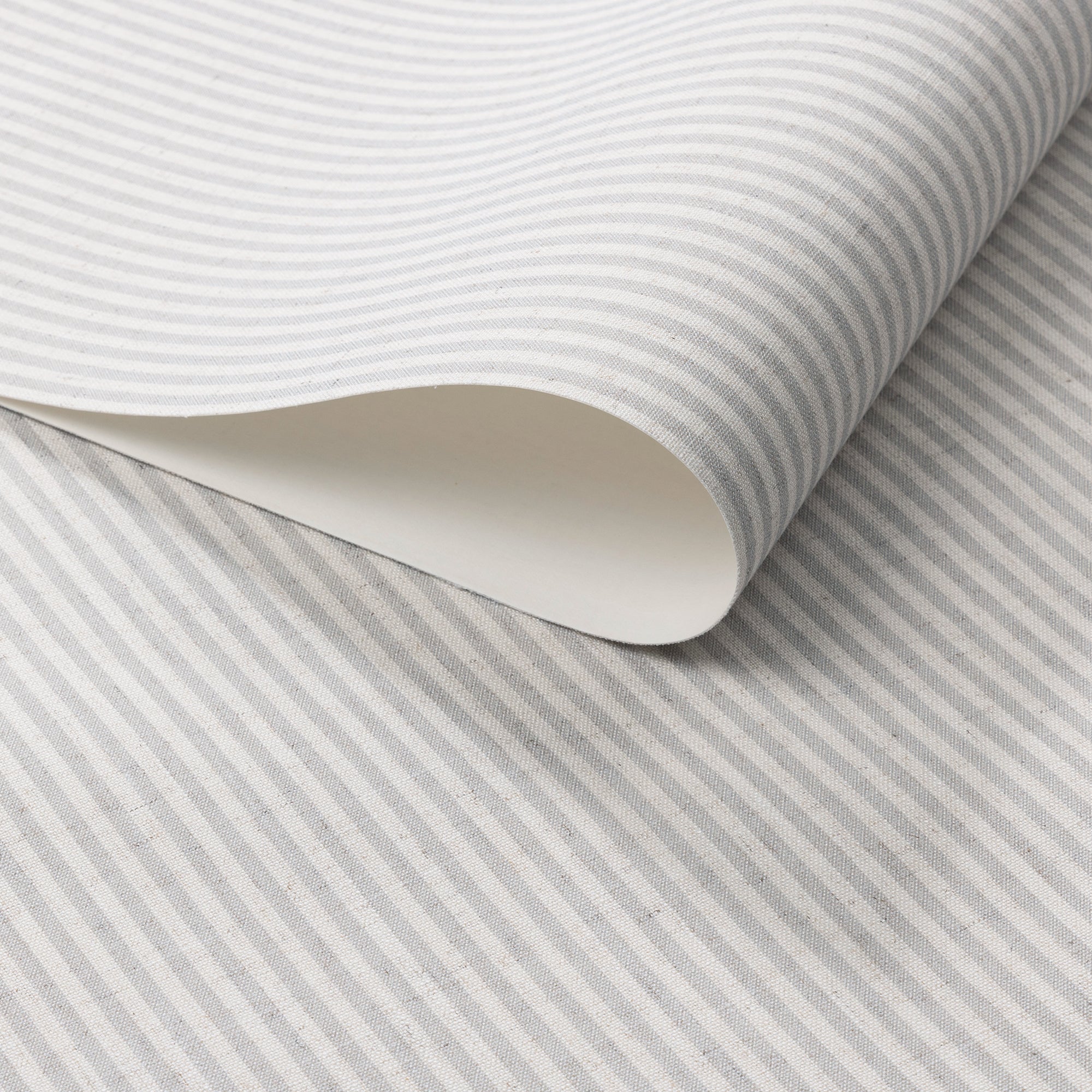 Close-up of wallpaper roll showcasing fine grey and off-white stripes on woven linen.