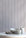 Interior scene with charcoal-striped linen wallpaper behind a marble table styled with handmade ceramic cups and a neutral linen napkin.