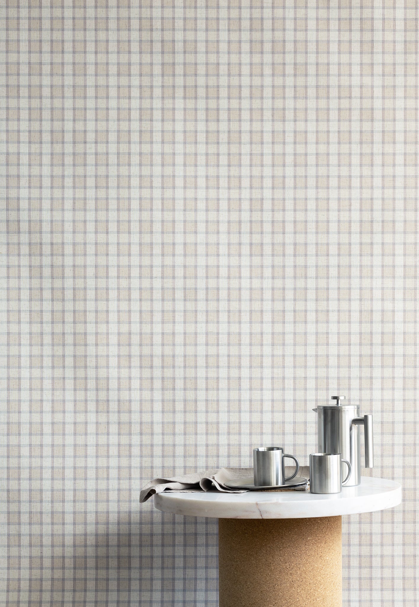 Interior shot of linen vintage plaid check wallpaper in soft neutrals, styled with a marble and cork table and stainless steel coffee accessories.