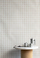 Interior shot of linen vintage plaid check wallpaper in soft neutrals, styled with a marble and cork table and stainless steel coffee accessories.