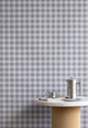 Interior scene with vintage plaid check linen wallpaper in blue and beige tones, styled with a marble and cork table and brushed metal coffee accessories.