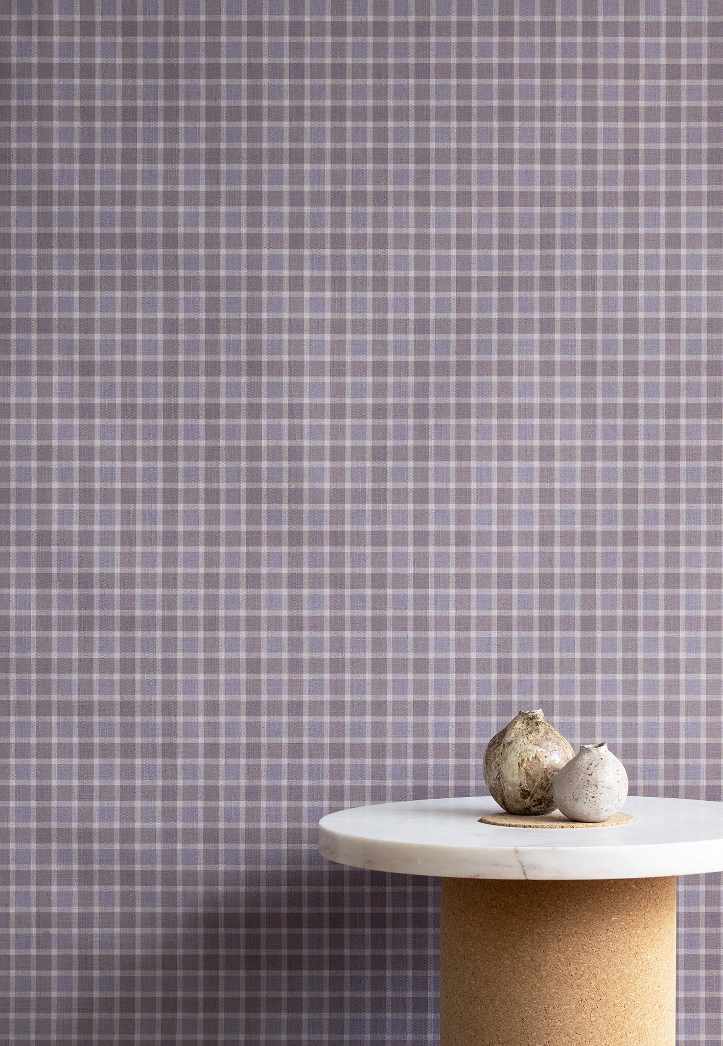 Interior styling with vintage plaid check linen wallpaper in lavender and taupe, paired with a marble and cork pedestal table topped with natural decorative elements.