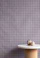 Interior styling with vintage plaid check linen wallpaper in lavender and taupe, paired with a marble and cork pedestal table topped with natural decorative elements.