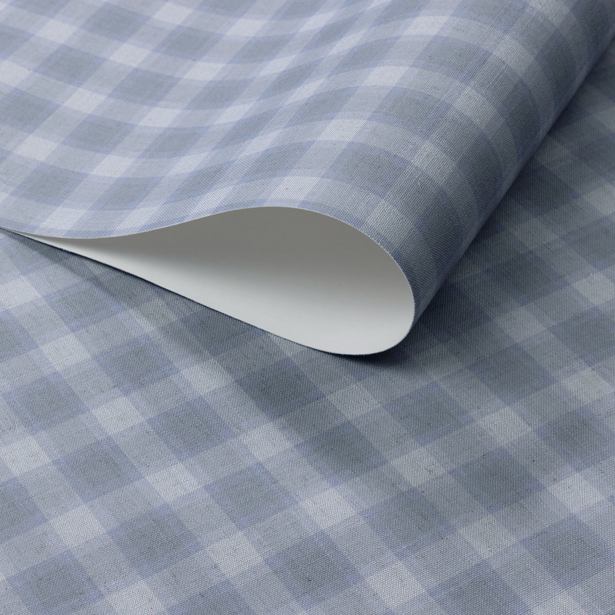 Close-up of vintage plaid check wallpaper in cool gray-blue and soft white tones with a linen-textured surface, shown with a rolled edge for detail.