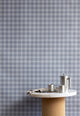 Interior setting with vintage plaid check linen wallpaper in cool gray-blue tones, styled with a marble and cork table and stainless steel coffee set.