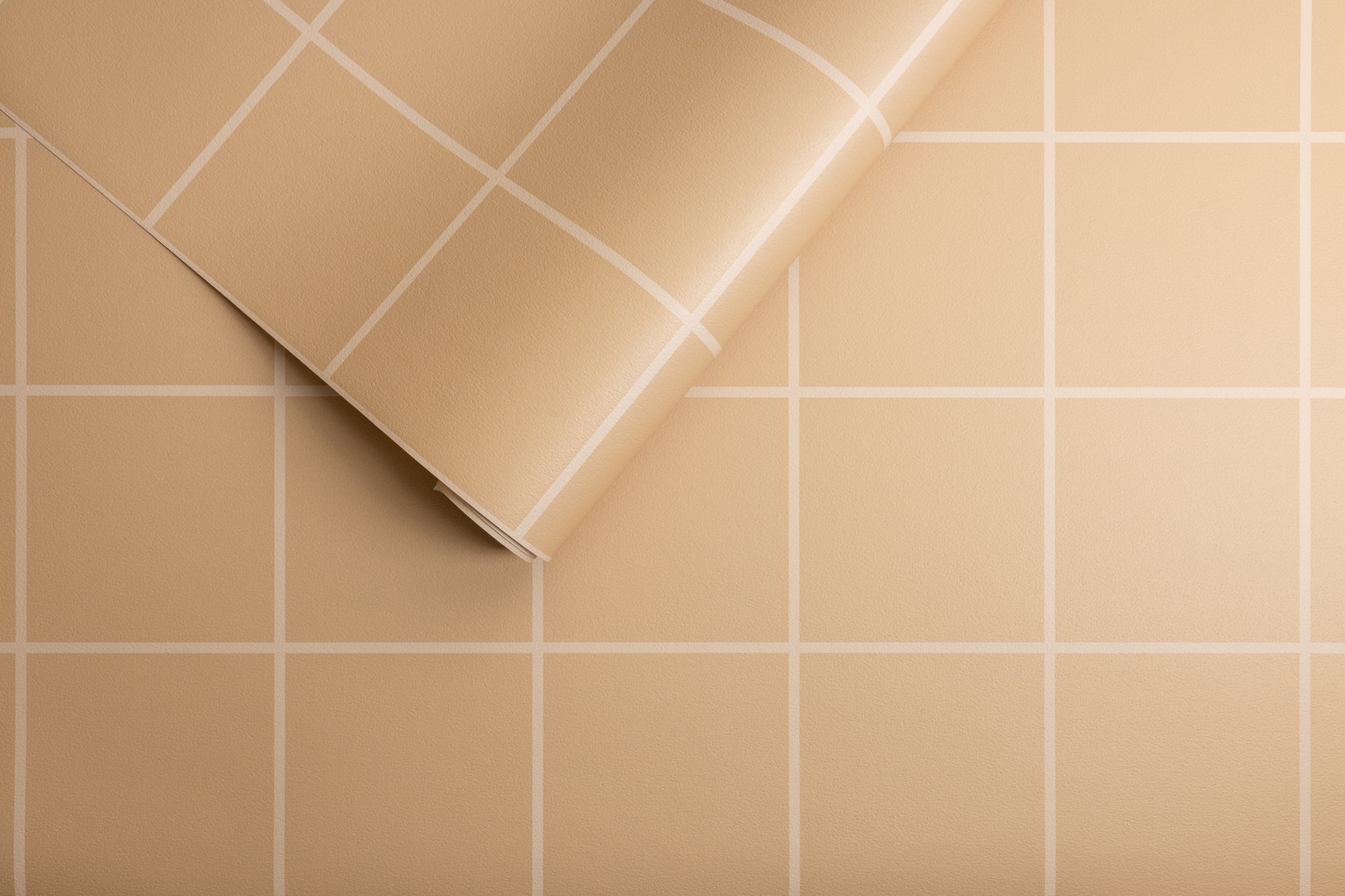 Beige wallpaper with a white grid pattern, partially unrolled to display its smooth, matte texture and precise geometric square design.