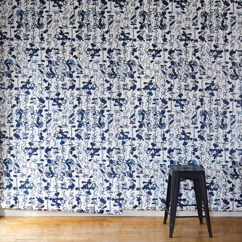 Modern interior featuring a bold abstract floral stripe wallpaper with black and blue hand-drawn botanical elements, paired with a sleek black stool for contrast