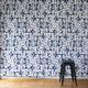 Modern interior featuring a bold abstract floral stripe wallpaper with black and blue hand-drawn botanical elements, paired with a sleek black stool for contrast