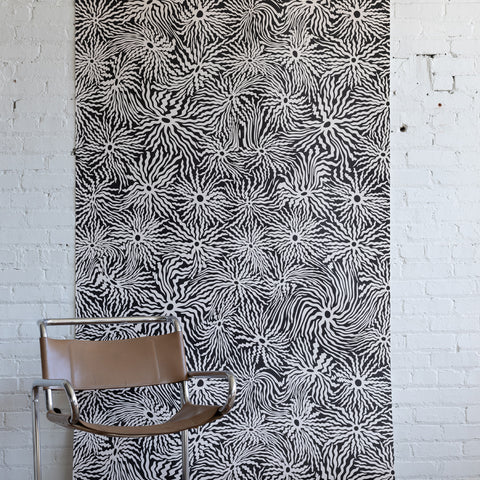 Modern interior featuring brown leather and chrome chair, black and white
patterned wallpaper with abstract swirl design, and light wooden flooring.