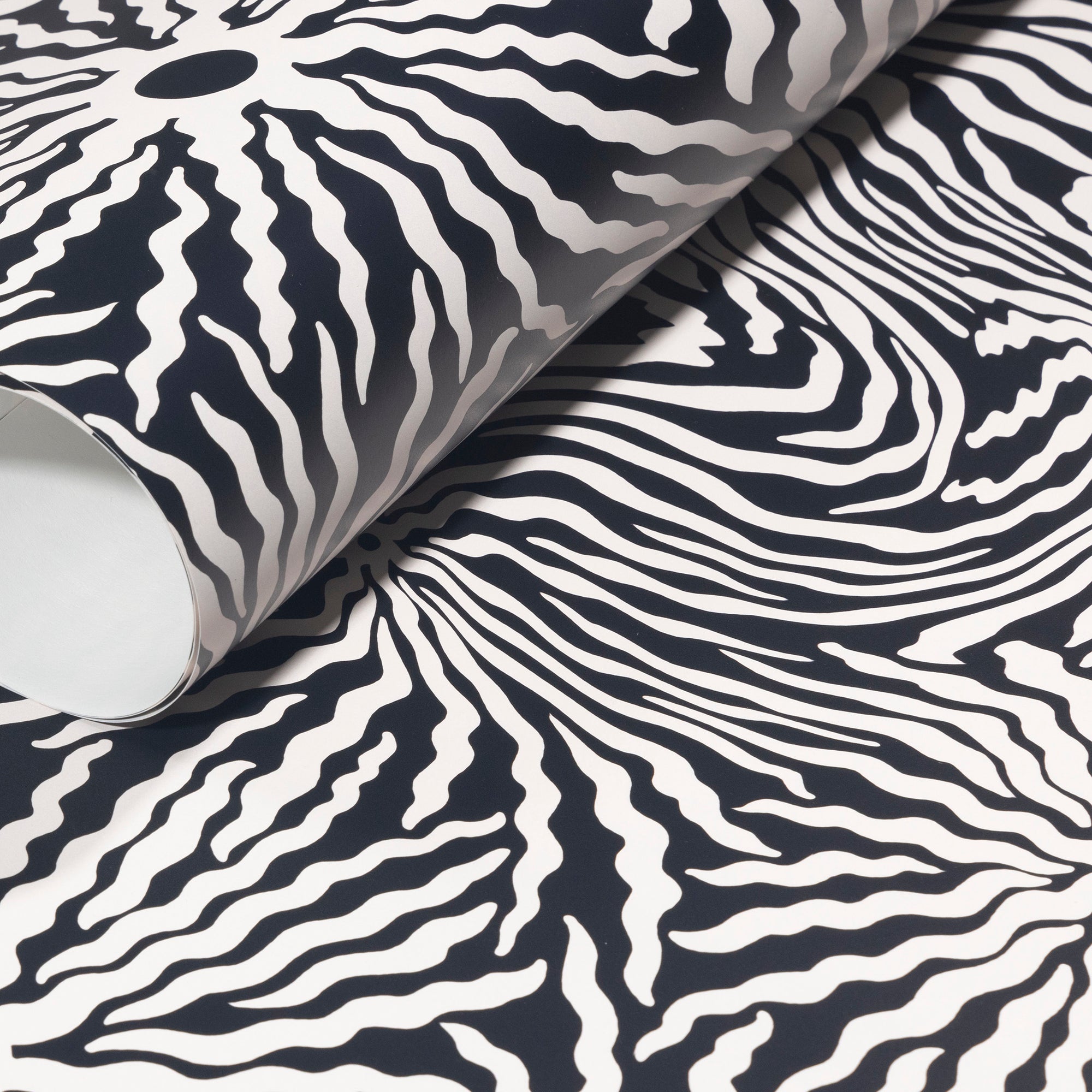 Rolled-up black and white wallpaper with bold wavy patterns, showcasing its
striking, contemporary aesthetic.
