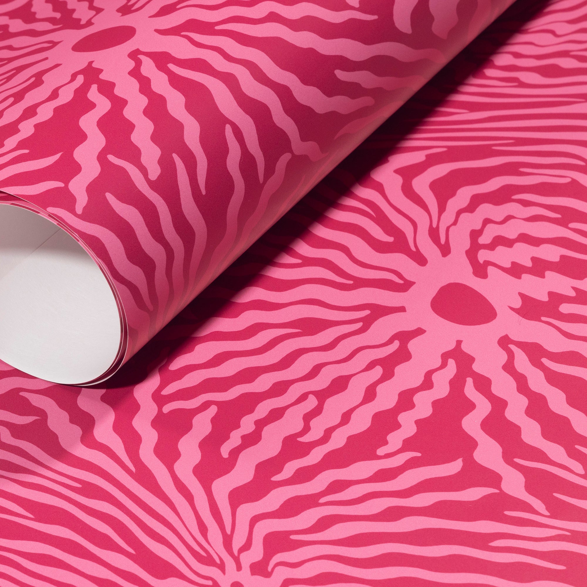 Rolled-up pink wallpaper with striking magenta wave-like patterns, emphasizing its bold and dynamic style.