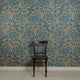 Room with silk wallpaper featuring a bold botanical pattern in deep blue and green tones, showcasing hand-painted flowers and leaves with white outlines, complemented by a black wooden chair in front.
