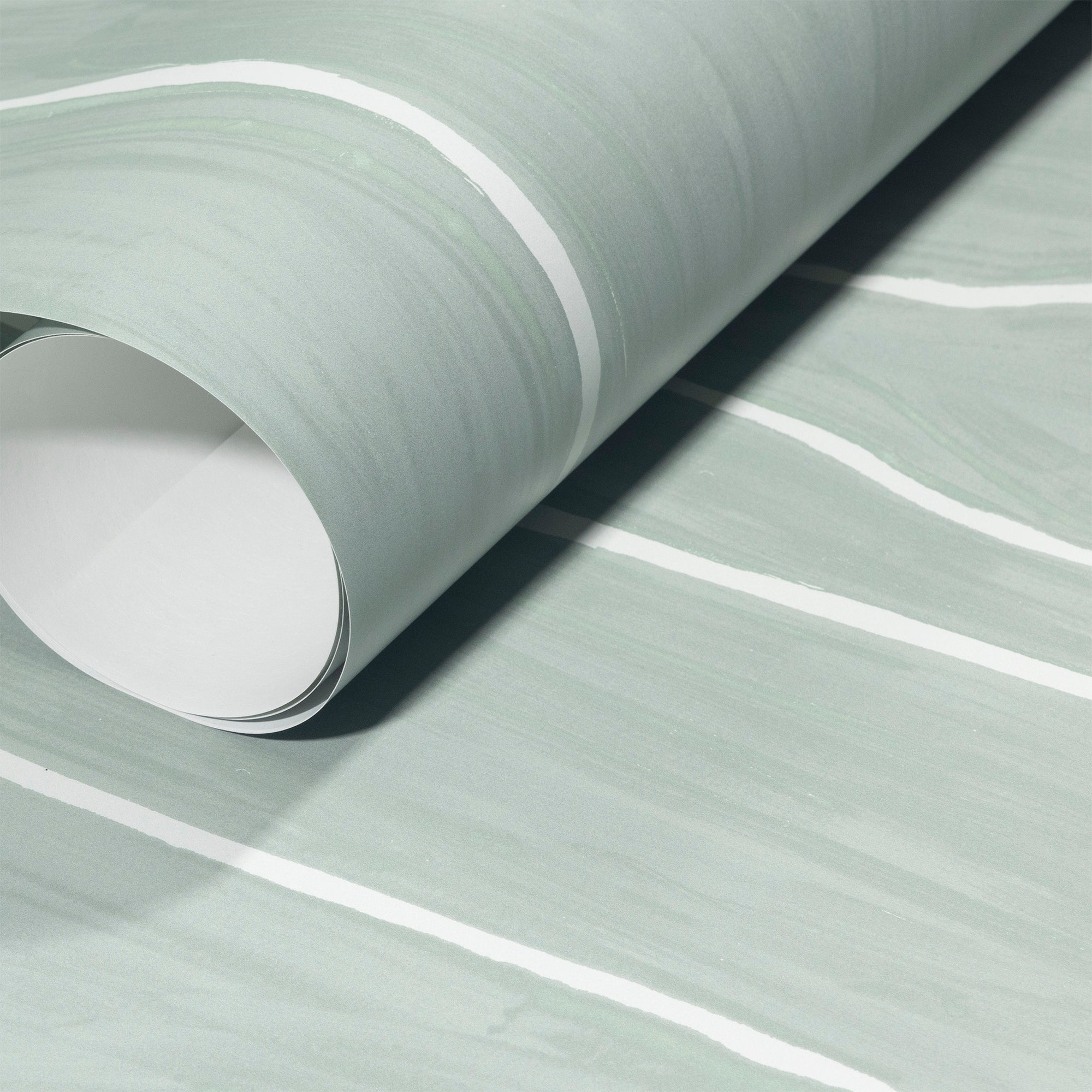 Rolled-up sage green wallpaper with white wavy vertical stripes, showing smooth texture and subtle color variations.